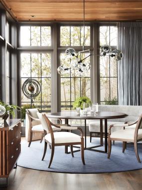 Room Scene: HC7243-10/HC7244-10 Pivot Dining Table shown in standard Truffle finish with Browned Steel base, HC7205-23 Saber Leg Dining Chair shown in  standard Truffle finish and in HC327 leather on back and arms and seat in HC4302-16 fabric, HC7207-72 Betty Banquette shown in standard Truffle finish and in HC251-60 fabric and HC7289-70 Plaited Chest shown in optional Dark Walnut finish with standard Blackened Steel base.